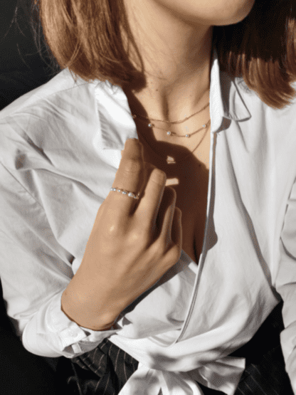 Na zdjęciu jest kobieta z pierścionkiem z perełek na dłoni.