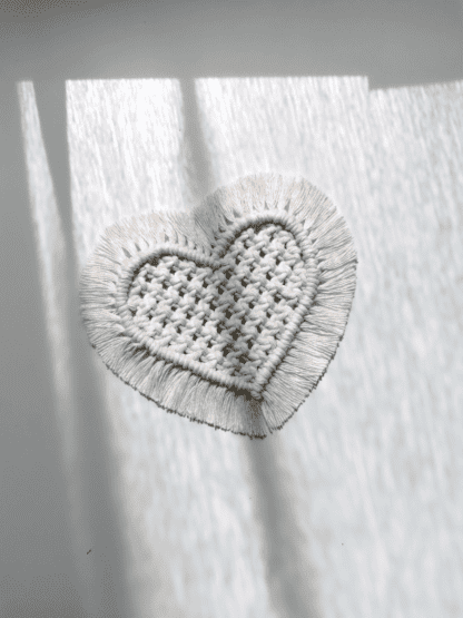 Na zdjęciu jest podkładka z makramy w kształcie serca.