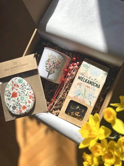 paczka prezentowa Wielkanocne kwiaty, w której znajduje się "herbata wielkanocna", kubek ceramiczny z malowanymi kwiatami oraz piernik w kształcie pisanki z namalowanymi kwiatami