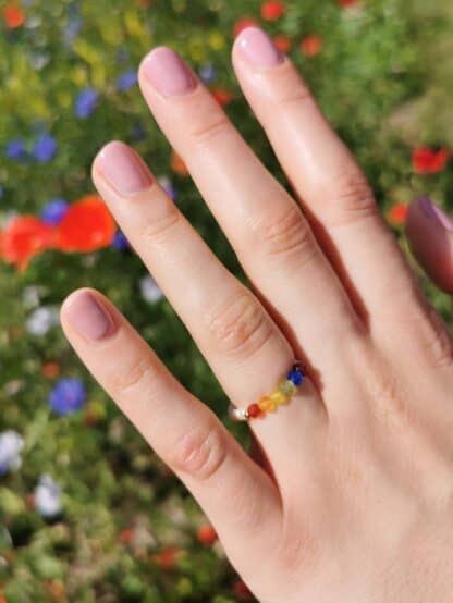 Na zdjęciu jest dłoń z tęczowym pierścionkiem Szczęśliwe Kolory