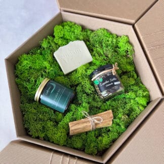 Na zdjęciu jest pudełko prezentowe "Święty spokój", w którym znajdują się: świeca sojowa, mydło naturalne, liściasta herbata i palo santo.