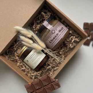 Na zdjęciu jest prezent "Pudełko czekoladek", zawierający krem orzechowo-czekoladowy oraz świecę sojową o zapachu czekolady.