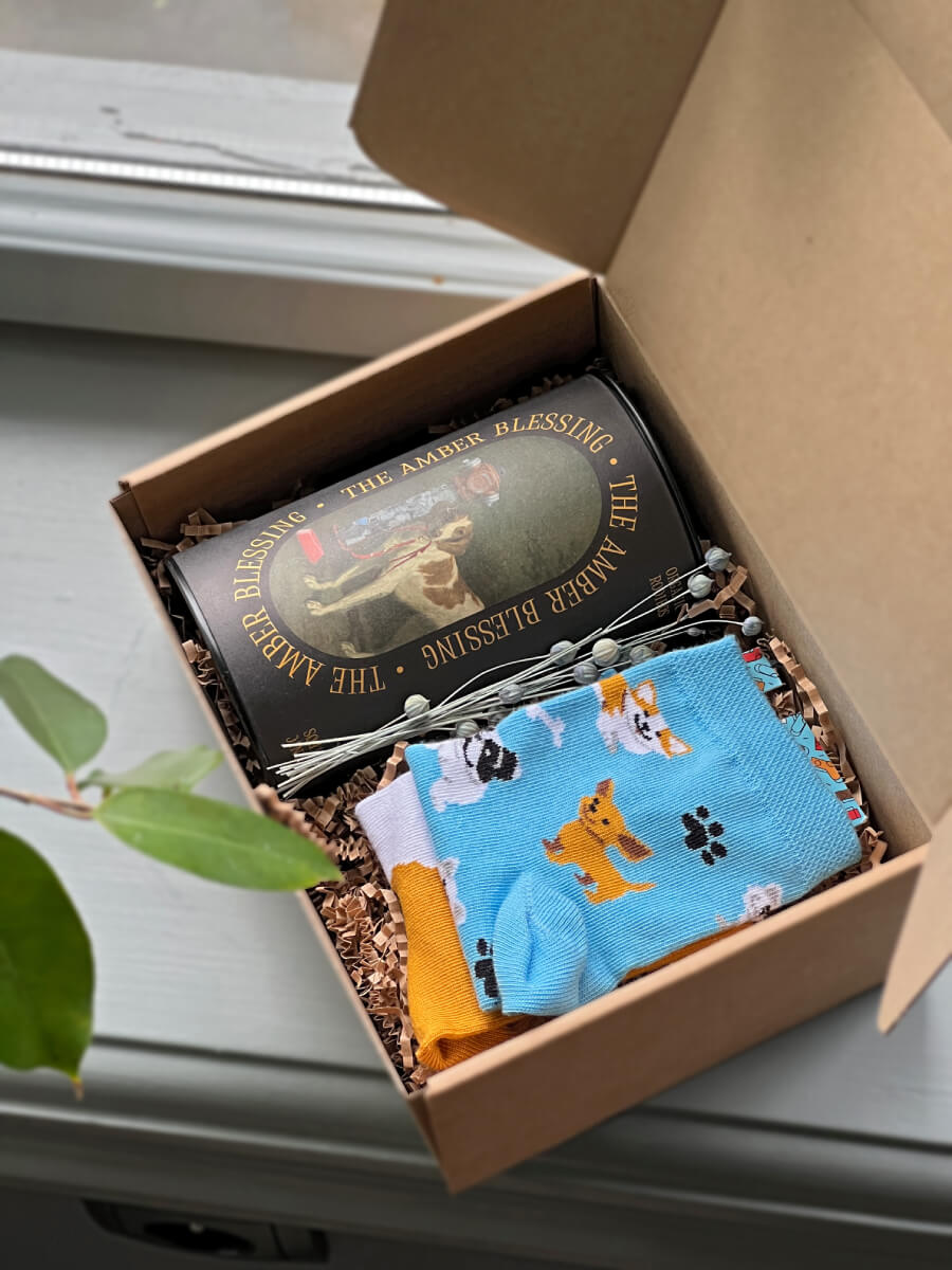 Na zdjęciu jest prezent dla psiarzy "Pieskie życie" z herbatą i kolorowymi skarpetkami